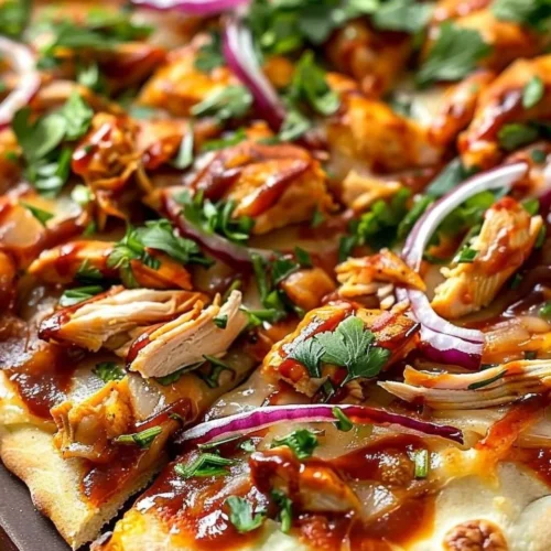 BBQ chicken flatbread topped with cheese and fresh ingredients on a wooden table