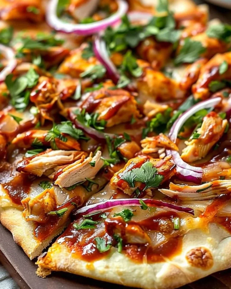 BBQ chicken flatbread topped with cheese and fresh ingredients on a wooden table