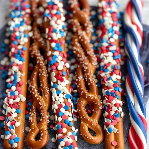 Patriotic pretzel rods dipped in red, white, and blue chocolate for a festive snack.