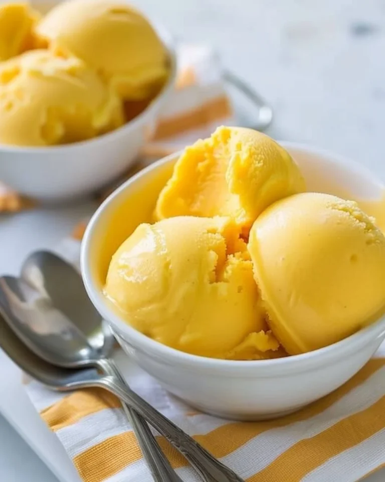 Homemade no-churn mango sorbet in a bowl with fresh mango slices